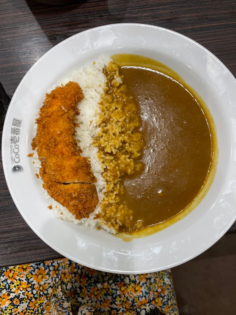 CoCo Ichibanya pork curry with rice and a breaded handmade chicken tender on a white plate